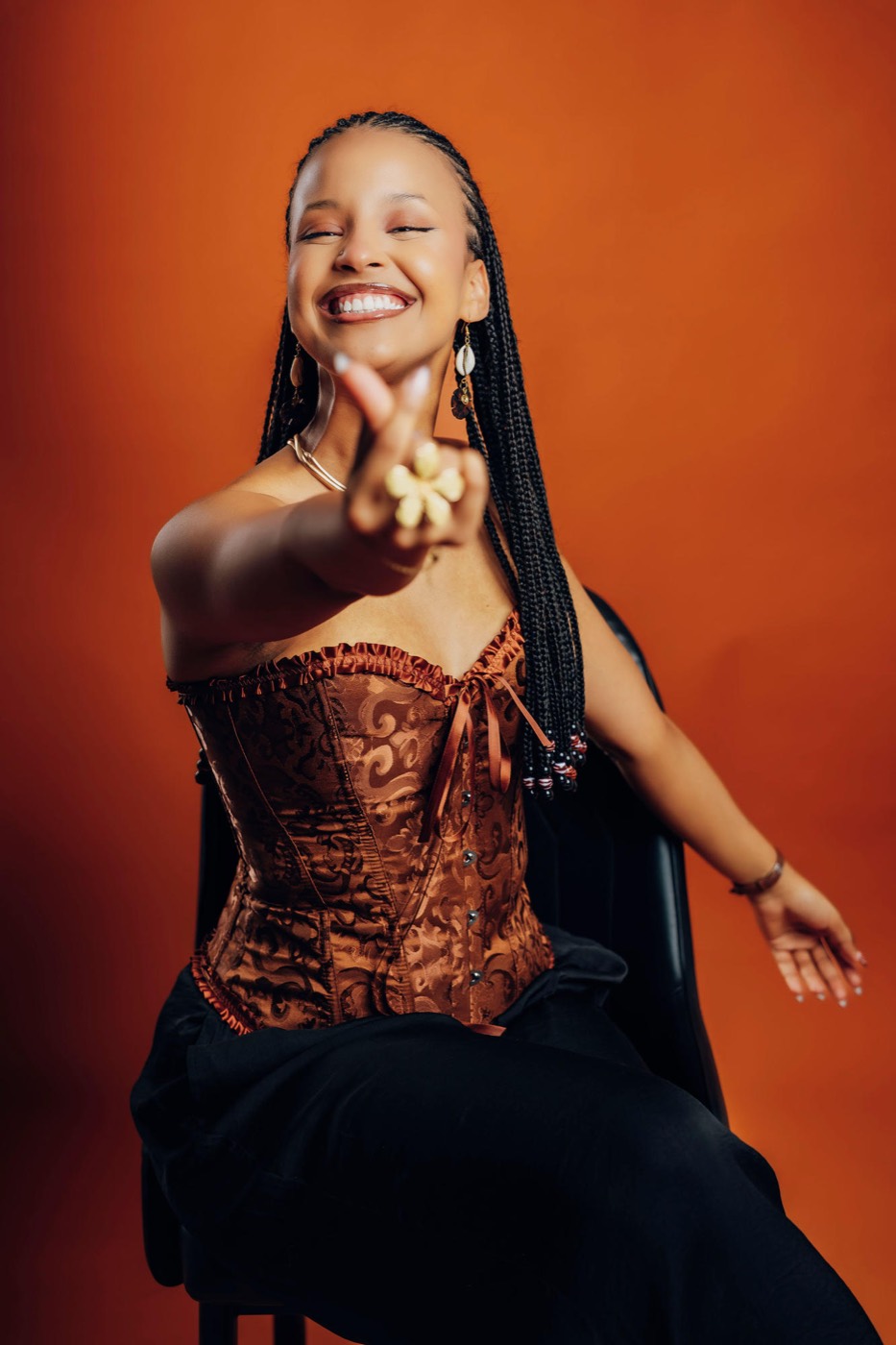 Marlène laughing and reaching toward the camera, against a warm terracotta backdrop